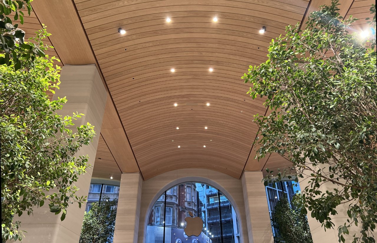 A series of 12 trees tower up over people's heads, and beneath this undulating wooden canopy