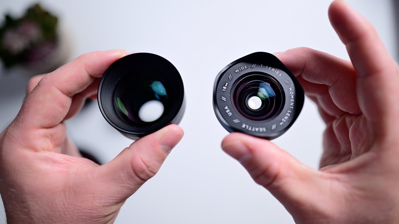 Holding two black mobile lenses above a white table