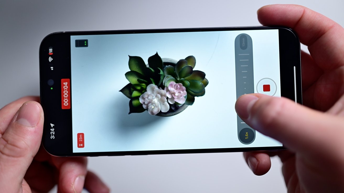 Showing Final Cut Camera on an iPhone held landscape above a white table, highlighting the zoom slider on the right-hand side