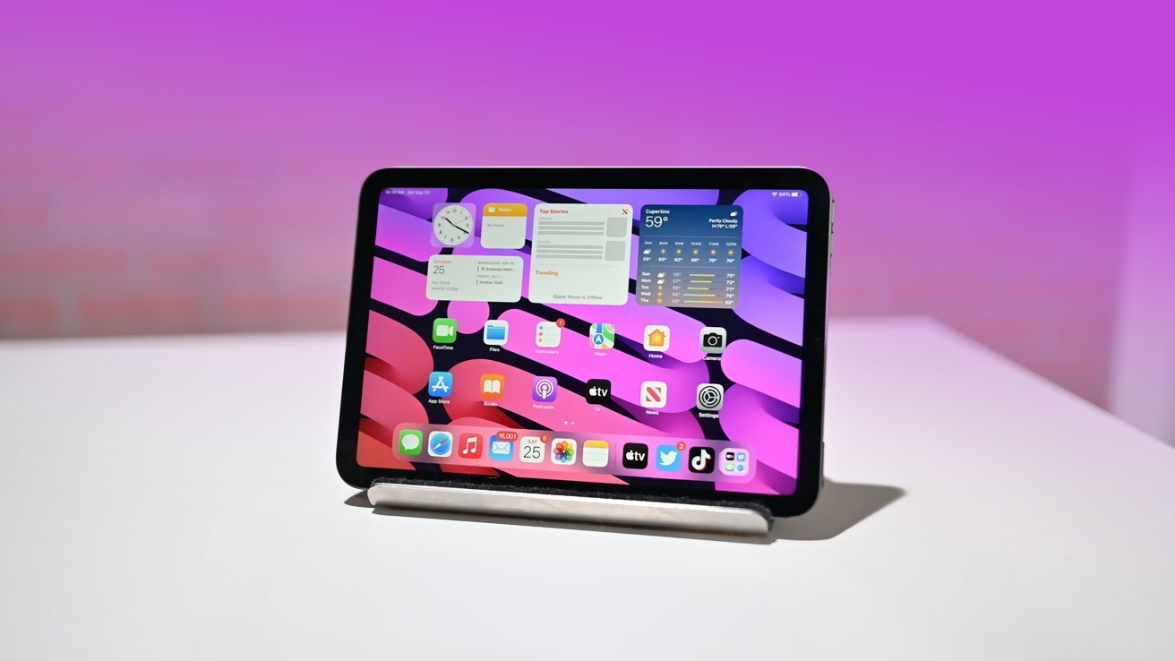 Tablet displaying a colorful home screen with multiple apps and widgets, placed on a white surface against a purplish background.