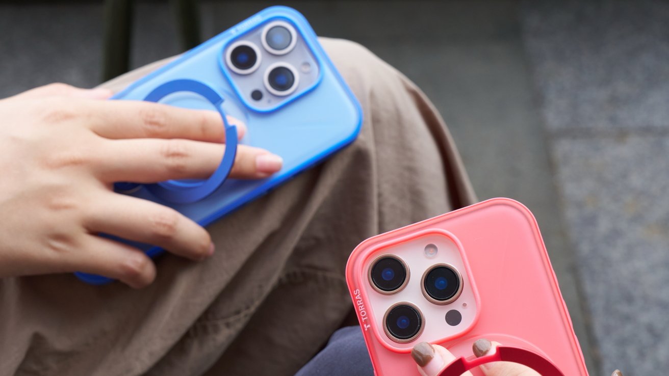 Two hands holding smartphones with colorful cases; one blue and one pink, each featuring a circular grip on the back.