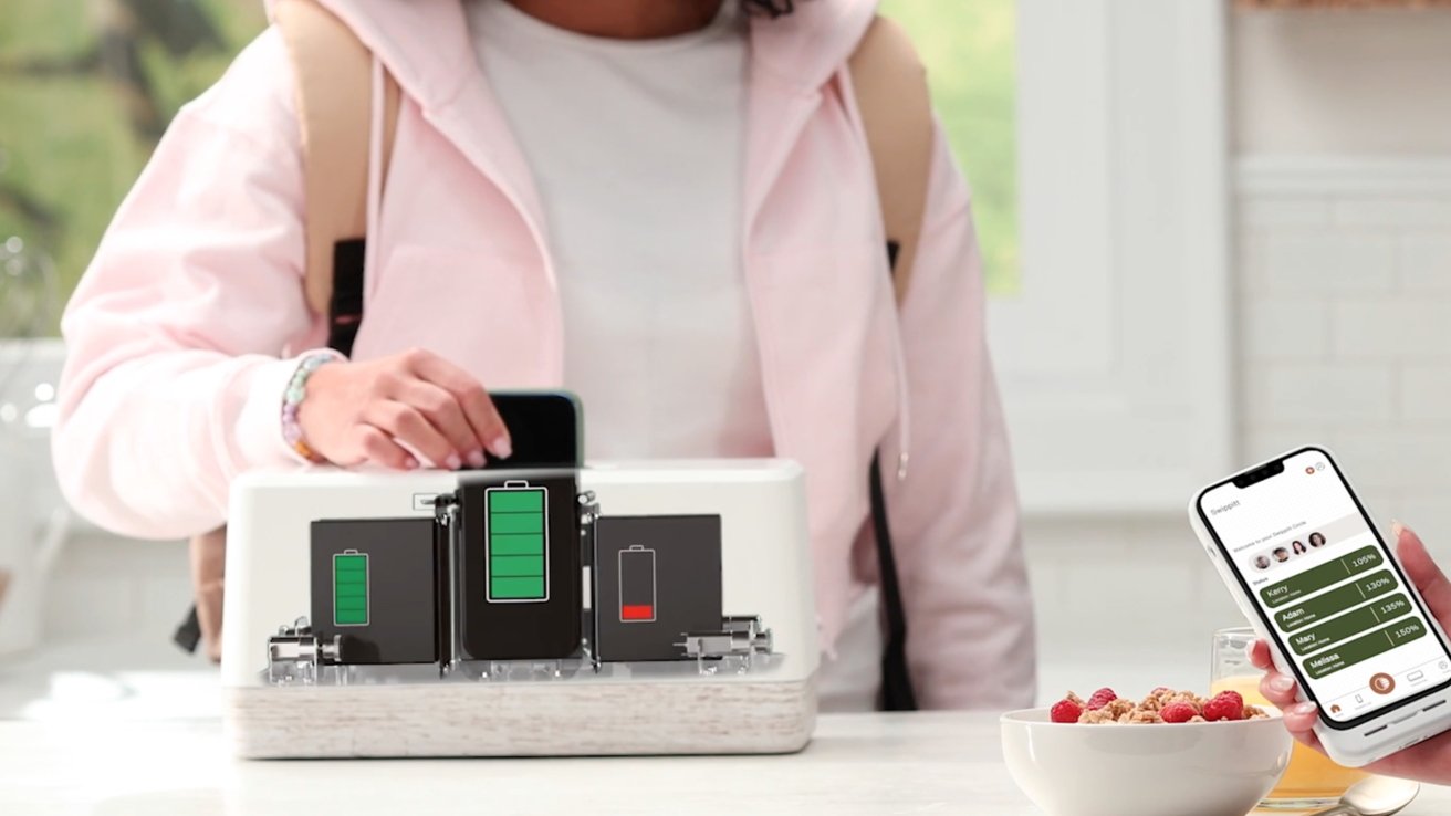 Person in pink hoodie charging device at home with a battery station, holding smartphone displaying charging progress alongside cereal bowl.