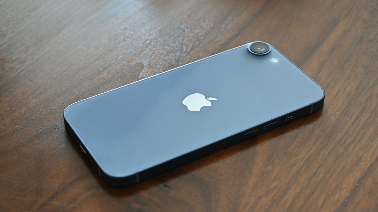 A smartphone with a gray back, prominent apple logo, and a single rear camera on a wooden surface.